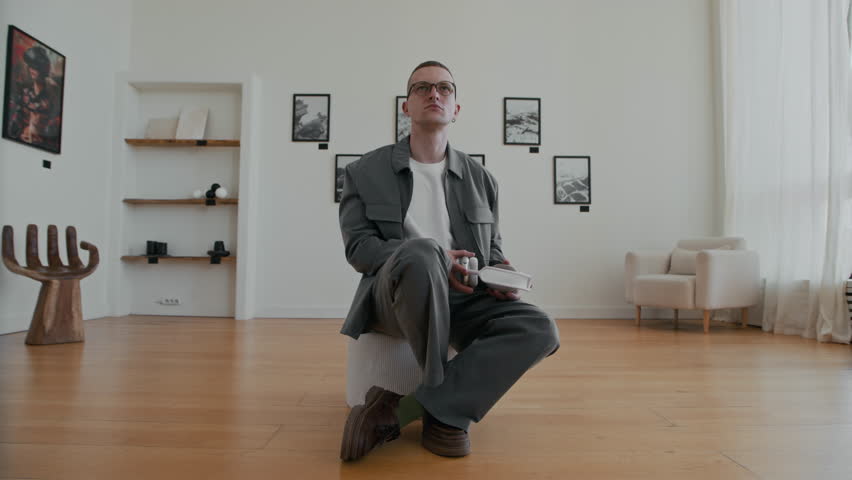 Minimal front view shot of trendy young man putting on big headphones while looking at art in modern art gallery slowmo