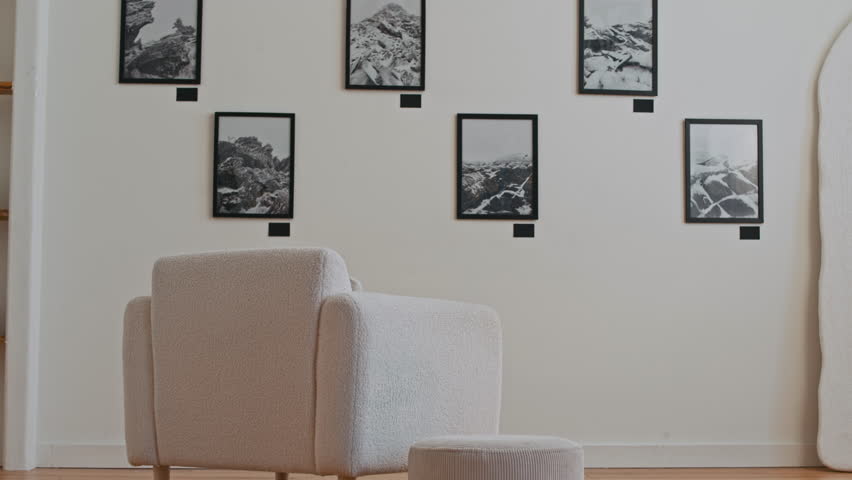 Back view of Caucasian young man walking into shot and sitting down in comfortable armchair looking at art on wall