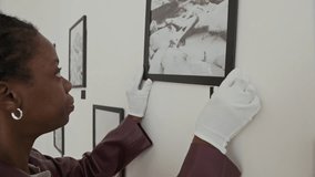 Side view closeup of two art gallery curators hanging art on walls and carefully cleaning frames while preparing for new exhibition - Powered by Shutterstock - Get 15% off with code: PIKWIZARD15