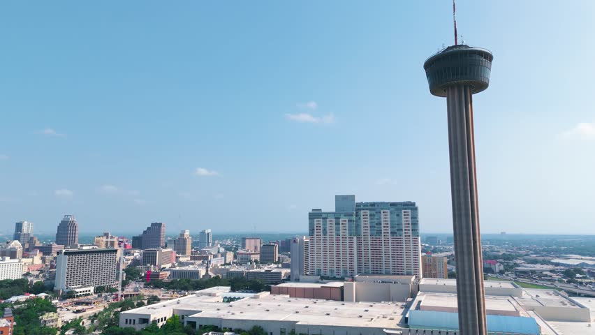 The Hemisfair Tower, also known as the Tower of Americas, sits in the heart of downtown San Antonio Texas surrounded by tall buildings, crowded highways and bustling city life.