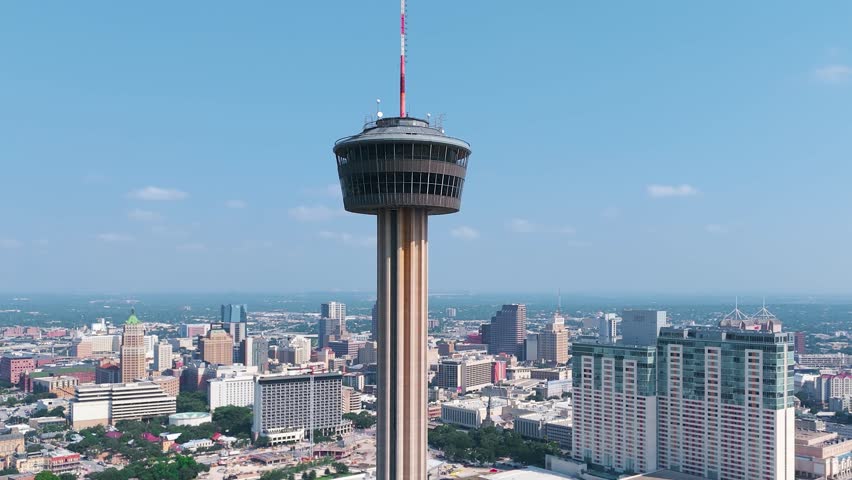 The Hemisfair Tower, also known as the Tower of Americas, sits in the heart of downtown San Antonio Texas surrounded by tall buildings, crowded highways and bustling city life.
