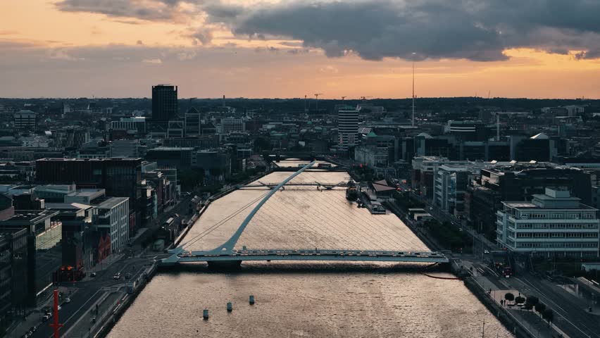 High approach toward Samuel Beckett Bridge with river mirroring sunset sky
