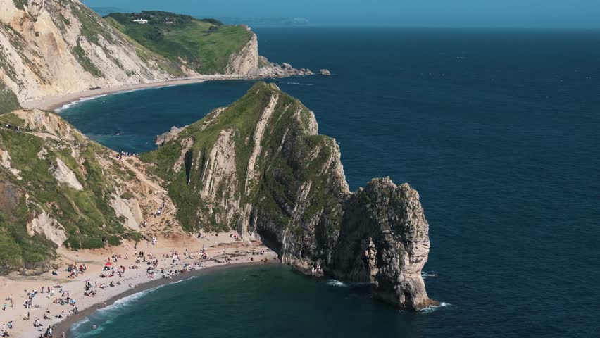 Wide orbit left above Durdle Door beach with birds flying below