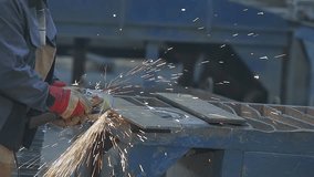 A worker grinds a metal plate or sheet with a hand grinder. Worker Grinding Metal Plate. Steel structure metalworking shop. Worker preparation steel plate by hand grinding machine. - Powered by Shutterstock - Get 15% off with code: PIKWIZARD15