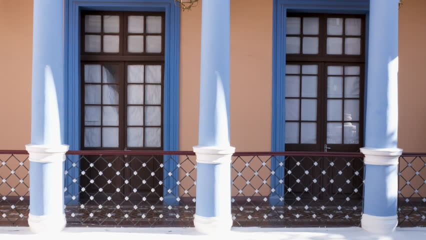 Traveler walks by blue colonial pillars at Museo Charcas in Sucre, Bolivia, exploring stunning architecture.