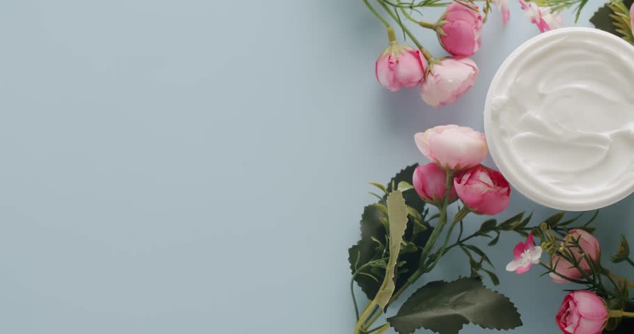 White Bottles and tubes with pink flowers for cosmetics pink on a light blue background in studio. Cosmetics oils based on natural ingredients, scrub, tonic, body care. Top view.