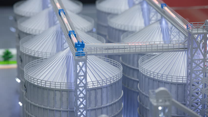 Detailed model of an industrial grain silo complex with metal storage bins, top conveyors, and support structures. Educational or presentation display showing logistics of agricultural grain handling.