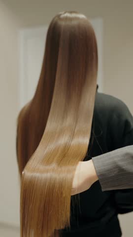 Combing a client's hair in a salon. Hair care, Combing Long, Silky Smooth Brown Hair in Salon. Hair Care and Beauty