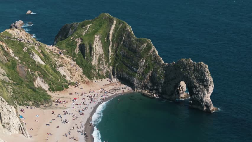 High aerial orbit right over Durdle Door beach and surrounding cliffs