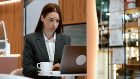 Businesswoman in gray blazer working on laptop in modern cafe. Concept of online consultations, remote freelance work, business education, and productivity. - Powered by Shutterstock - Get 15% off with code: PIKWIZARD15