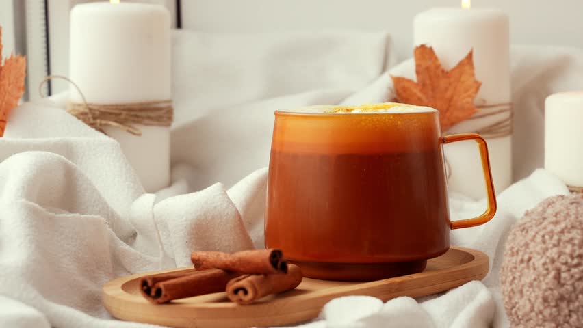 Adding whipped cream Seasonal drink cacao coffee with whipped cream and cinnamon sticks Thanksgiving and Hello Fall Halloween concept. Celebrating autumn holidays at cozy home on the windowsill
