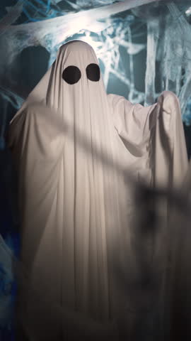 funny halloween ghost in white sheet actively dancing in dark corridor with cobweb. Scary halloween concept