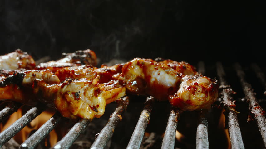 Spicy Chicken Wings on Fire. Grilling over Charcoal with BBQ Sauce