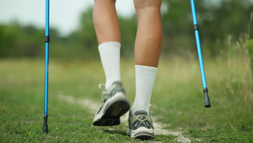 Legs In Motion During Nordic Walking On Trail. Athletic Calves, Running Shoes , Trekking Poles. Outdoor Fitness Activity. Healthy Lifestyle Endurance Training, Cardio Wellness Nature Exercise Fitness
