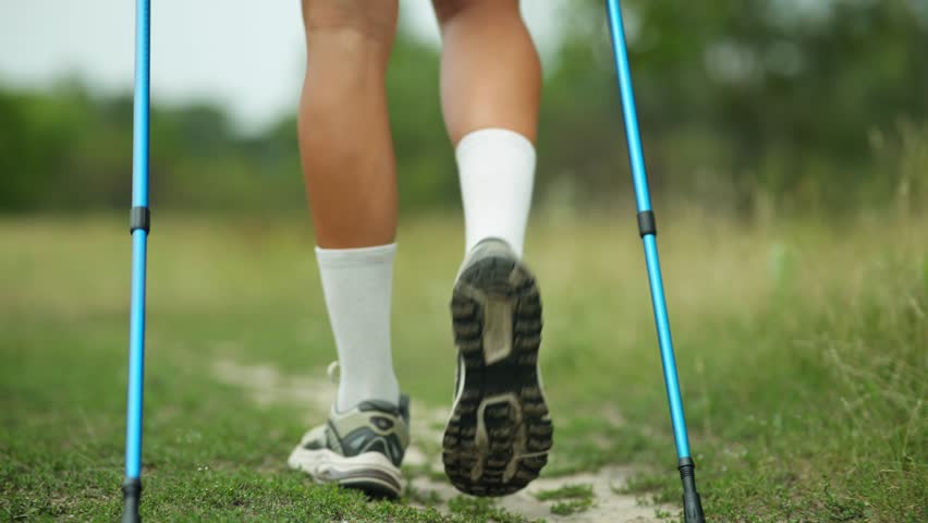 Legs In Motion During Nordic Walking On Trail. Athletic Calves, Running Shoes , Trekking Poles. Outdoor Fitness Activity. Healthy Lifestyle Endurance Training, Cardio Wellness Nature Exercise Fitness