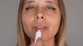Close-up of a young blonde woman applying lip balm to her dry lips. A gentle moment of self-care and hydration, focusing on natural beauty and daily skincare - Powered by Shutterstock - Get 15% off with code: PIKWIZARD15
