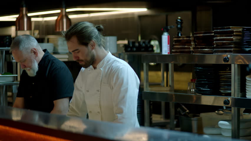 Portrait of Caucasian male chef working on busy commercial restaurant kitchen. Shot with 2x anamorphic lens