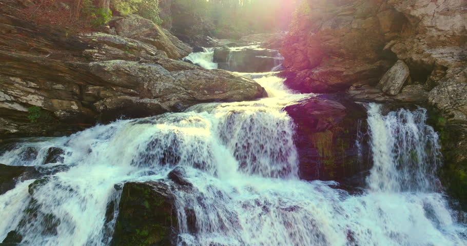 Beautiful waterfall in Appalachian mountains. Autumn beauty at Cullasaja Falls in Nantahala National Forest. Rushing river water and steep cliffs bordered by colorful deciduous trees