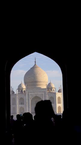 Vertical shot crowd silhouette shooting the Taj mahal through an archway at the entrance of the monument compound showing the majestic wonder in India