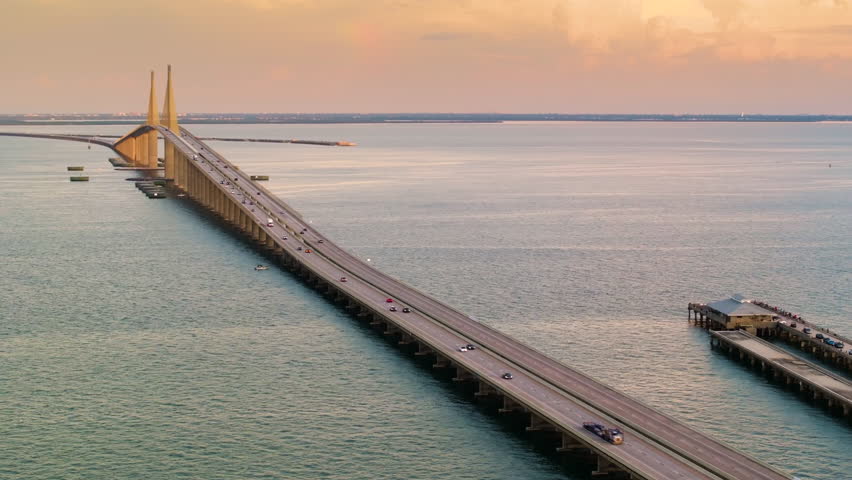 Highway road with driving traffic cars at sunset on Sunshine Skyway Bridge over Tampa Bay in Florida. Transportation infrastructure in USA