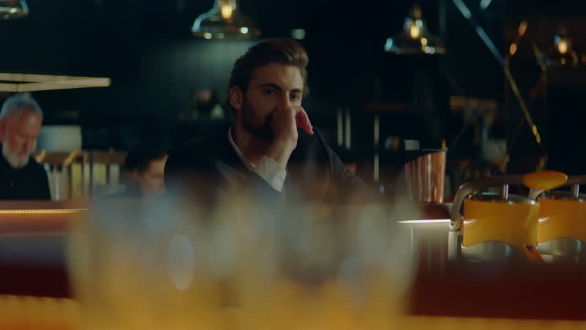 Beautiful Caucasian male sitting in a stylish restaurant, drinking cocktail. Shot with 2x anamorphic lens