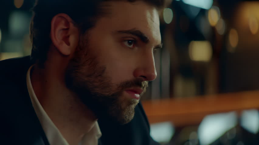 Beautiful Caucasian male sitting in a stylish restaurant, drinking cocktail. Shot with 2x anamorphic lens