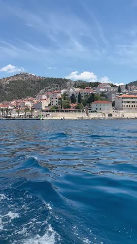 Video of Hvar Croatia coastline with hillside homes and waterfront buildings seen from a boat on calm blue sea