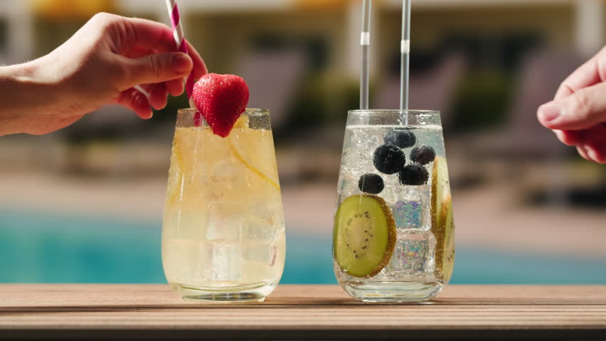 Fruit cocktail in hotel bar, Two cocktail glasses cheers in the hands on sea background. Bartenter making drink in bar, Summer vacation concept, A beautiful couple enjoy the vacation at the beach.