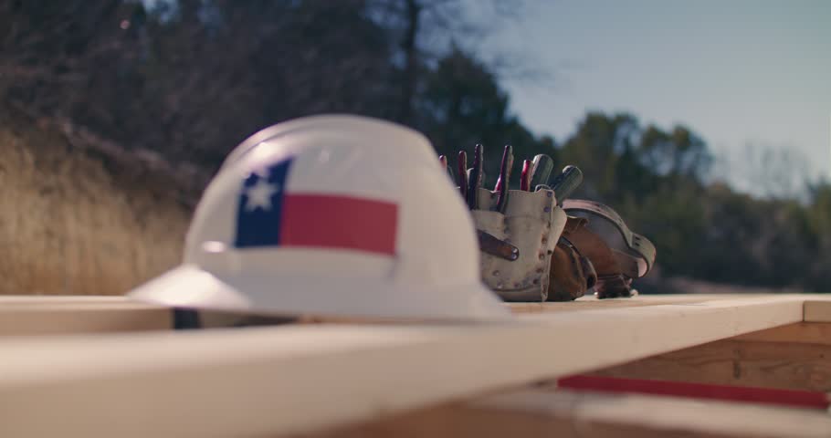 Close Up of Construction Hard Hat With Texas Flag Sticker Near Tool Belt On Wooden Plank at Construction Site