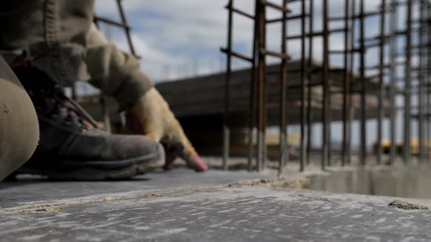 Worker driving nail into plywood with hammer at building site