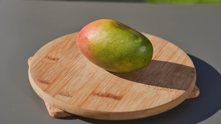chef cuts fresh ripe mango on cutting board to prepare a healthy meal. outdoor cooking, food closeup