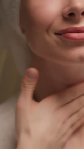 Happy beautiful Caucasian young woman applying body cream rubbing neck skincare gorgeous female model in bath towel bathrobe apply lotion cosmetic massaging soft skin care beauty routine home bathroom