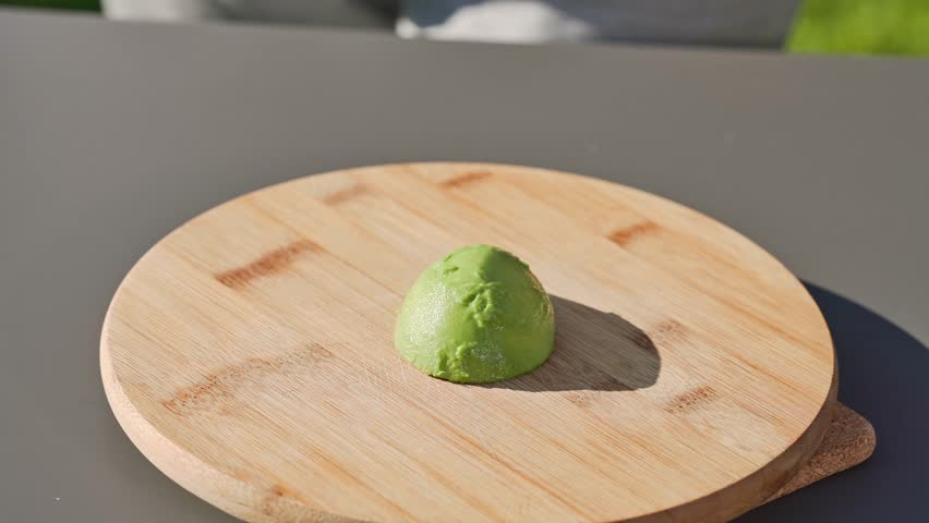 chef cuts fresh green avocado on cutting board to prepare a healthy meal. outdoor cooking, food closeup