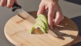 chef cuts fresh green avocado on cutting board to prepare a healthy meal. outdoor cooking, food closeup - Powered by Shutterstock - Get 15% off with code: PIKWIZARD15