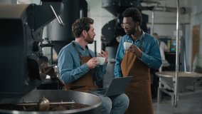 Two factory workers Caucasian African men drinking coffee work break discussing roasting machine use laptop together workplace equipment production talk conversation quality control caffeine process - Powered by Shutterstock - Get 15% off with code: PIKWIZARD15