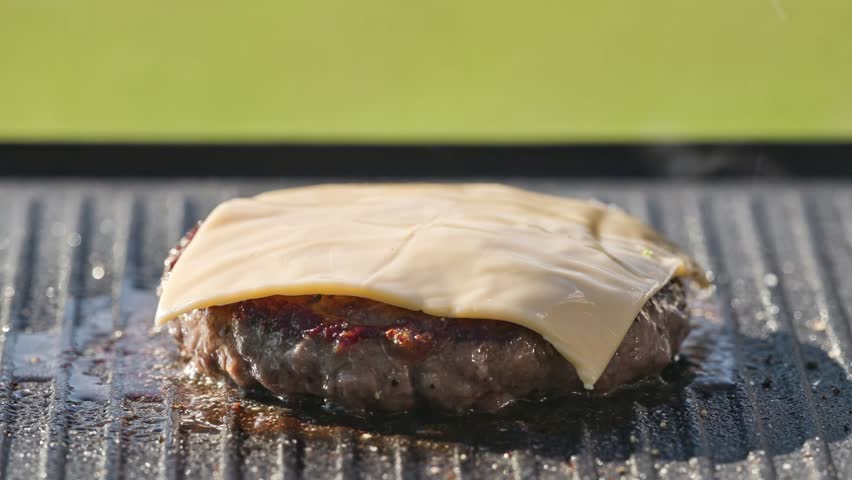 cook preparing fresh burger meat with melted cheese on hot grill in garden for making healthy meal, food closeup, outdoor cooking