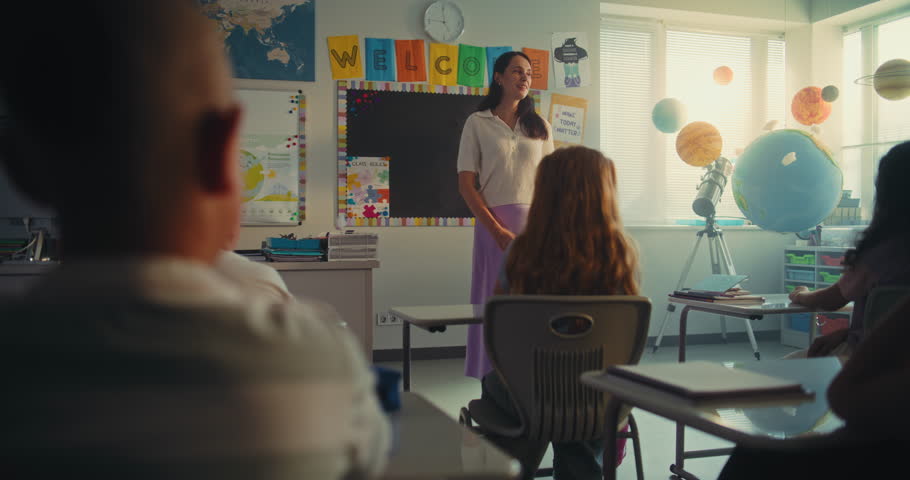 STEM Class on Renewable Energy: Female Teacher Educating Ecology to Diverse Elementary School Children. Talented Girl Talking, Presenting Homework in Front of Classroom Full of Classmates. Dolly Shot.