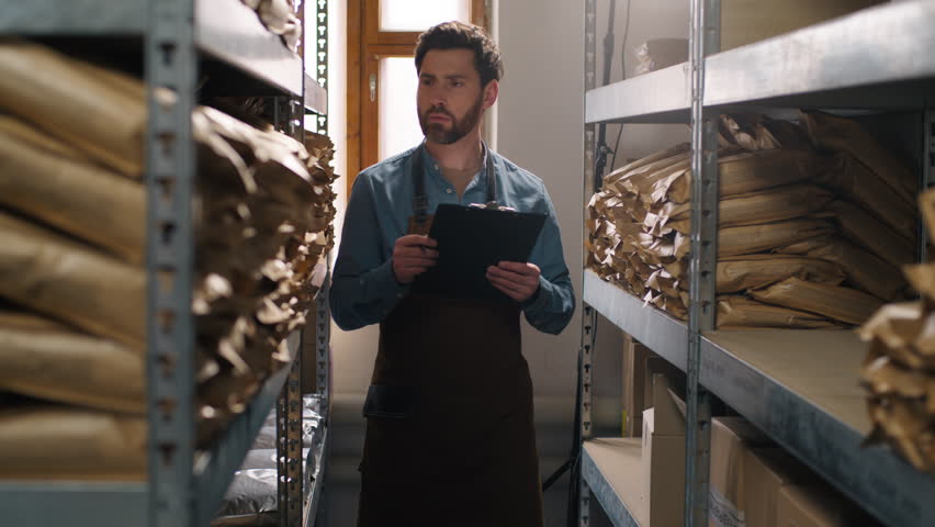 Caucasian man male guy clipboard inventory inspection coffee warehouse packaging shelf factory storage entrepreneur control beans caffeine small business product workplace beverage supply manufacture