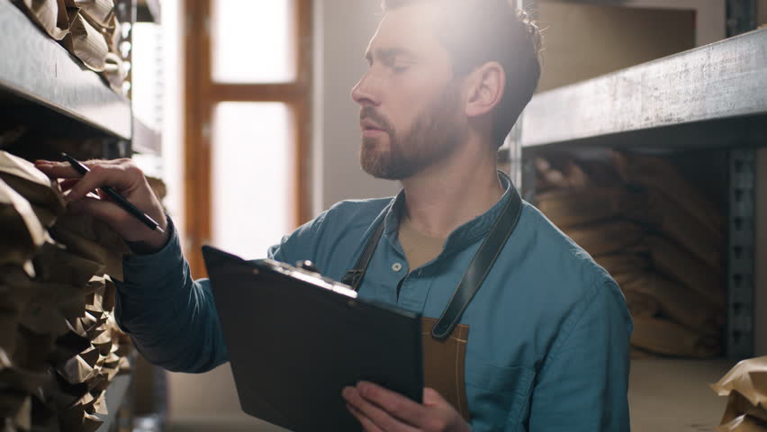 Caucasian man male guy clipboard inventory inspection coffee warehouse packaging shelf factory storage entrepreneur control beans caffeine small business product workplace beverage supply manufacture - Powered by Shutterstock - Get 15% off with code: PIKWIZARD15