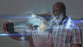 Senior couple raising phone for selfie while light streaks showing technology on beach. Romance, connection, serenity, digitalart, lifestyle, outdoor, harmony - Powered by Shutterstock - Get 15% off with code: PIKWIZARD15