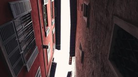 Camera moves backward while pointing up between narrow buildings. Colorful facades with shutters contrast a rough stone wall. Urban canyon feeling - Powered by Shutterstock - Get 15% off with code: PIKWIZARD15