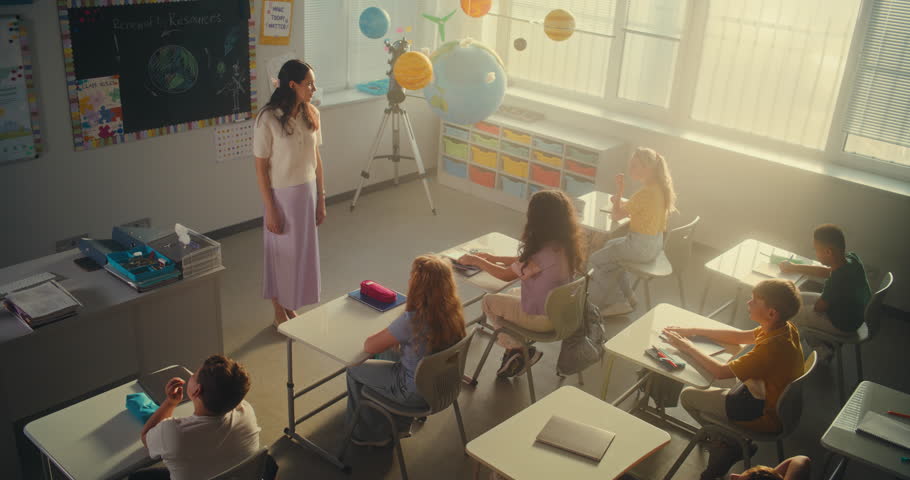 Female Teacher Finishing Lesson, Saying Goodbye to Group of Diverse Kids at the End of School Day. Happy Primary School Children Packing Their Backpacks and Leaving School for Holidays. High Angle.