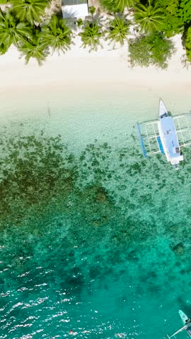 Boat running over the transparent turquoise water. Pasandigan Cove. Cadlao Island. El Nido. Palawan, Philippines. Vertical view.