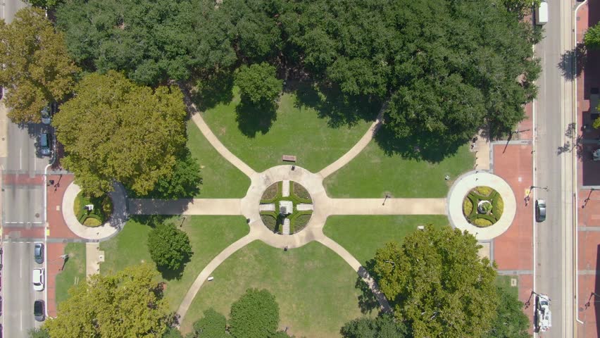 An aerial drone shot above Lafayette Square in the Central Business District of New Orleans, Louisiana. The shot showcases the symmetry of the park design, featuring the bronze statue of Henry Clay.