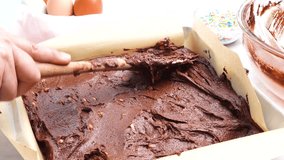 Baking chocolate brownies and using a spatula to spread out the batter. Making brownies on a white background and batter in the square baking pan. In the kitchen making a chocolate dessert. - Powered by Shutterstock - Get 15% off with code: PIKWIZARD15