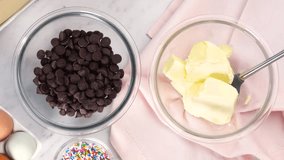Baking chocolate brownies and adding butter to the semi-sweet chocolate chips to melt. Making brownies on a white background surrounded by eggs, pink napkin and a baking pan. Putting butter in a bowl - Powered by Shutterstock - Get 15% off with code: PIKWIZARD15