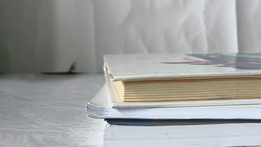 Female hands place an old book on the stacks of books lying on the table. Learning. School textbooks.