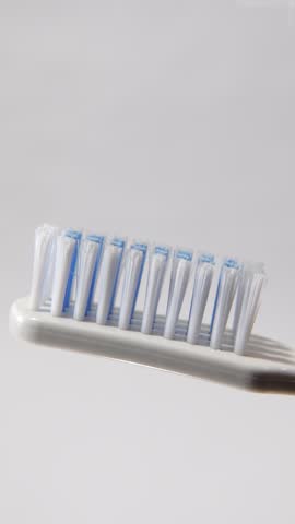 Toothpaste being smoothly applied to the bristles of a toothbrush. Toothbrush with Toothpaste Applied on Bristles