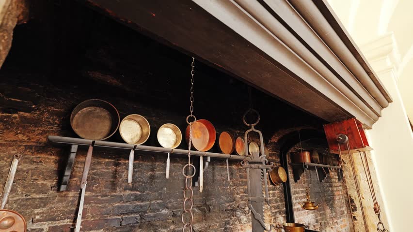 Baroque kitchen wall with aged bricks, cookware, chains, rustic fireplace frame