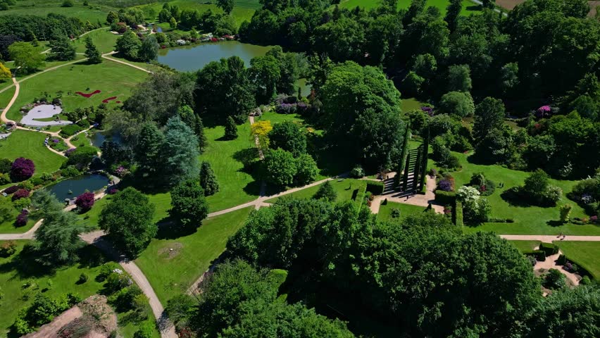 Parc de Haute Bretagne, lawns, ponds, diverse trees, Brittany in France. Aerial drone forward